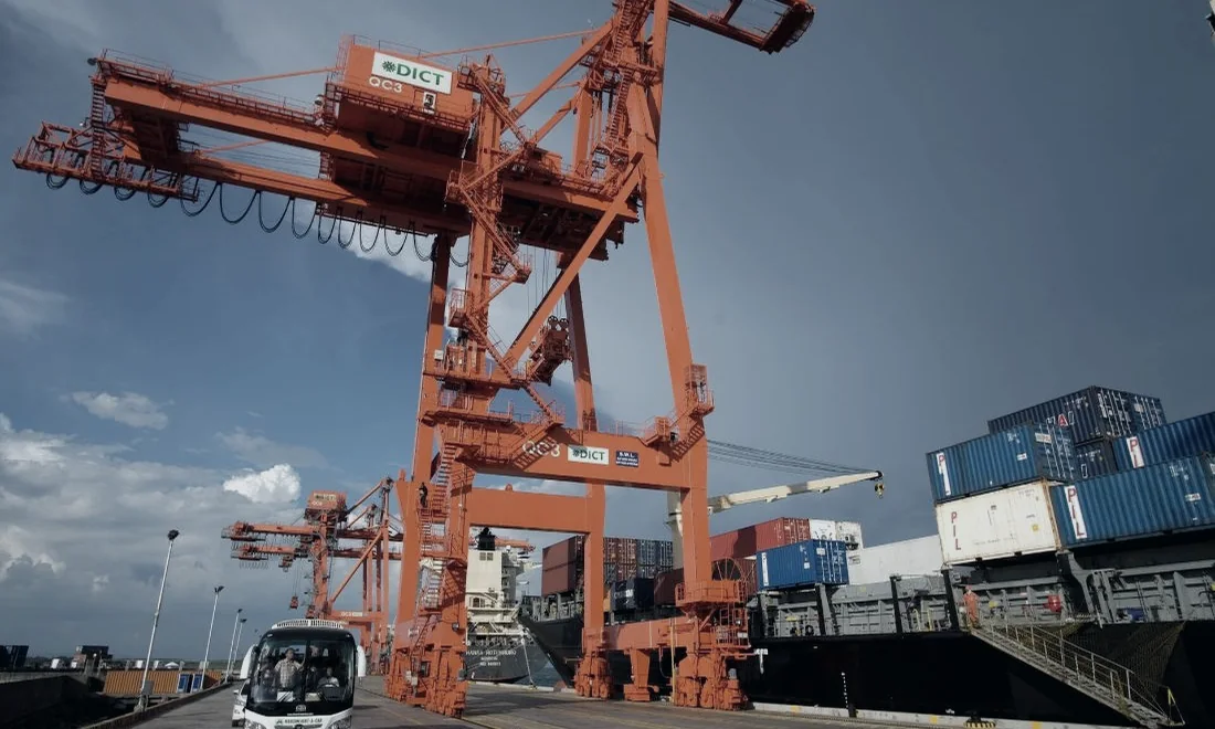 Ship-to-shore cranes over stacked containers at a port terminal.
