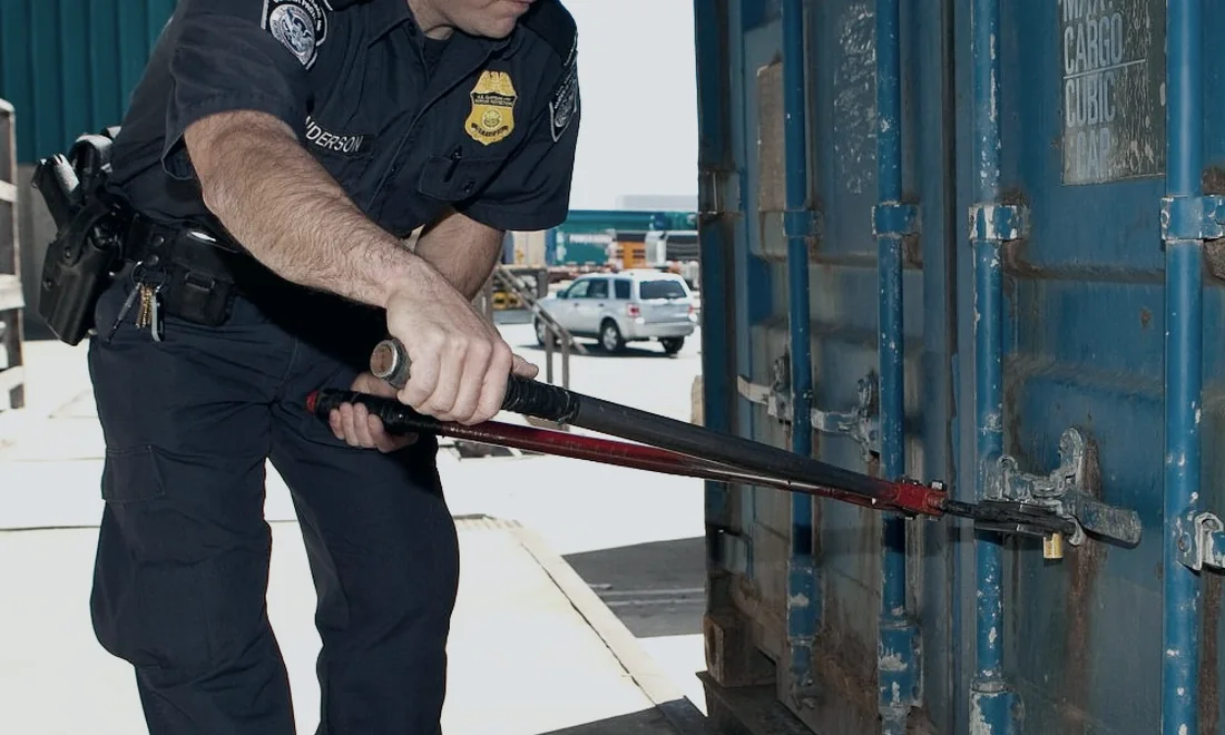 A customs officer cutting the seal on a shipping container.